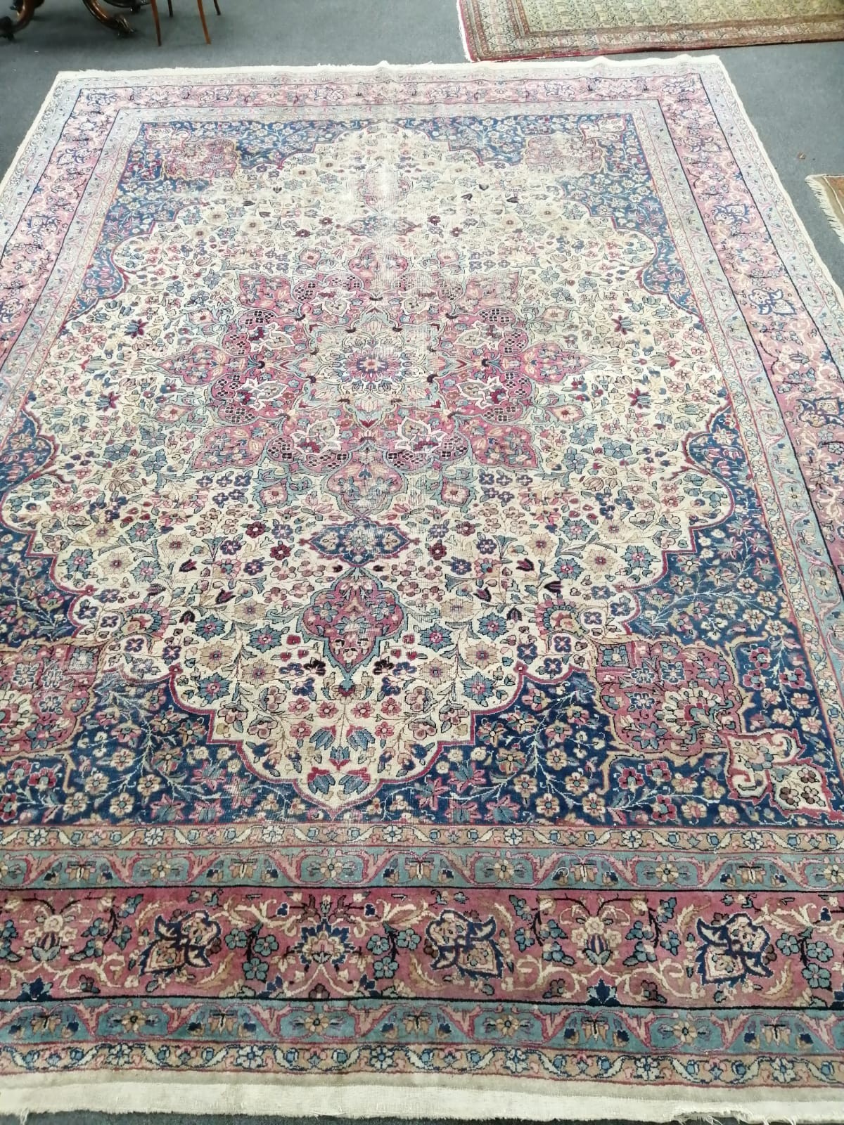 A Persian ivory ground carpet with central medallion of floral motifs, multi-bordered, 400 x 291cm